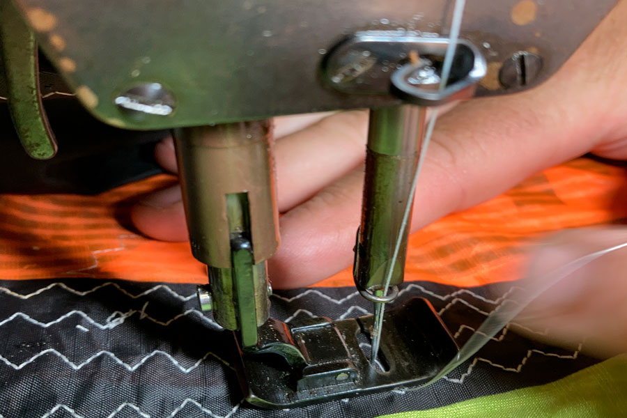 Imagen detalle de la parte de la aguja de una máquina de coser con la que se está reparando el borde de aqtaque de una cometa de Kite Surf
